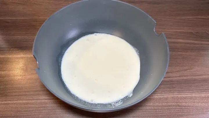 Zuerst darf die Sahne in die Schüssel. Wiege 200 Milliliter Sahne mit einer Küchenwaage ab oder wenn du einen Becher Sahne hast, gib den ganzen Becher rein. Da ist nämlich genauso viel drin, wie wir brauchen. Zuerst wird die Sahne in die Schüssel gegeben zum Zubereiten der Spaghetti-Muffins.