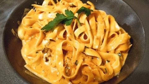 Eine cremige Pasta mit breiten Bandnudeln in einer schmackhaften Sauce, garniert mit frischer Petersilie.