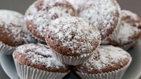 Süße Schokomuffins mit Puderzucker überzogen liegen auf einem Teller, bereit zum genussvollen Verzehr.