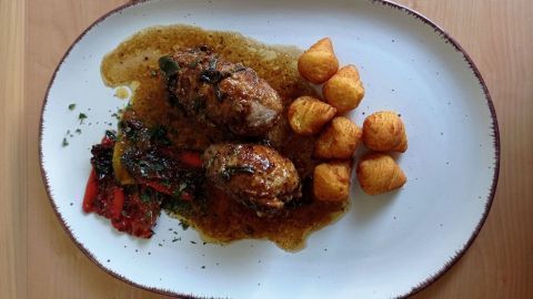 Kalbfleischrouladen sind mit Parmaschinken und Salbei serviert, begleitet von Röstkartoffeln und Gemüse auf einem weißen Teller.