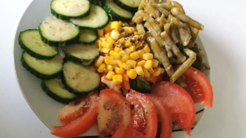 Salatbowl zeigt geschnittene Gurken, Tomaten, Mais und Bohnen, die auf einem Teller schön arrangiert sind.