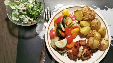 Ofenschmaus mit Hähnchenstreifen: Saftige Hähnchenstücke mit buntem Ofengemüse und goldbraunen Kartoffeln, serviert mit einem frischen Feldsalat mit Tomaten. Perfekt für ein ausgewogenes und leckeres Abendessen.