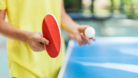 Junge macht einen Aufschlag beim Tischtennis.